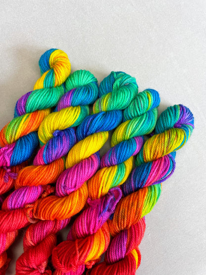 5 x 20g Hand-dyed Yarn mini skeins in colourway Bright Rainbow. The image shows a close up view of the twisted skeins on our DK weight Yarn Base. The yarn contains 7 bright colours, sunshine, lava, ruby, apple, cyan, electric purple and neon pink and photographed on a white background.